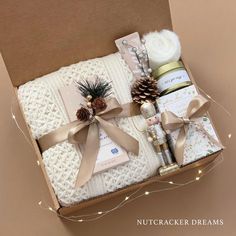 an open box with various items wrapped in ribbon and lights on the side, including pine cones