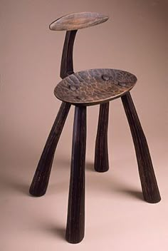 a wooden chair sitting on top of a white floor next to a brown wall in front of it