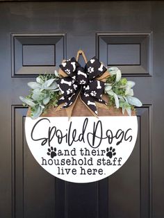 a black and white door hanger that says spoiled dogs and their household staff live here