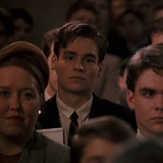 a group of people sitting next to each other in front of a man wearing a suit and tie