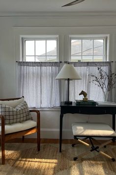 a room with two chairs and a desk in front of three windows that have blinds on them