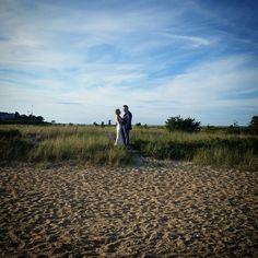 a bride and groom are standing in the sand on their wedding day at the beach