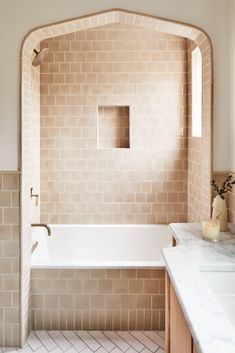 a bathroom with a bathtub, sink and window in the wall is shown here