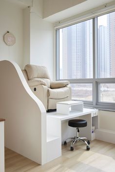 a living room with a couch, chair and desk in front of a large window