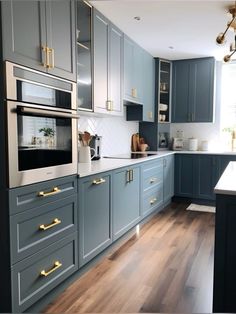 a kitchen with blue cabinets and gold handles on the ovens, counter tops, and wood flooring