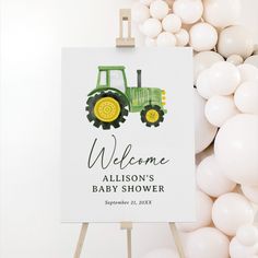 a welcome sign for a baby's shower with balloons around it and a tractor in the background