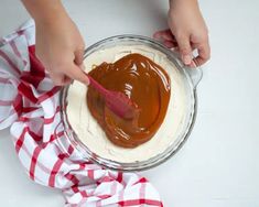 someone is spreading caramel on top of whipped cream in a glass bowl with a spoon