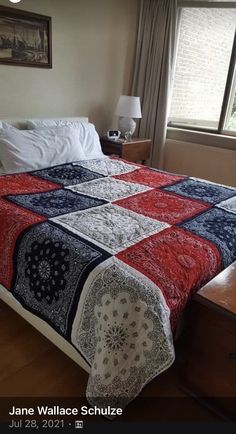 a bed with a red, white and blue bedspread on top of it