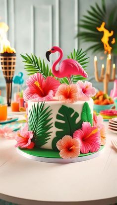 a cake decorated with flowers and flamingos is sitting on a table in front of candles