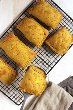 four pastries cooling on a wire rack next to a cloth and napkin with two forks