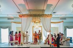 a group of people that are standing in front of a wedding ceremony stage with flowers on it