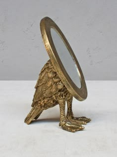 an antique brass magnifying glass with a bird figurine