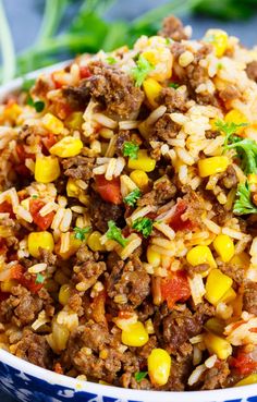 a blue and white bowl filled with rice, meat and corn on top of it