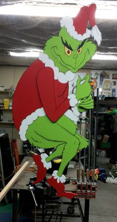 the grinch is sitting on top of an assembly line in his office wearing a santa hat and red pants