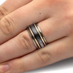 a person's hand with two rings on their wedding ring, one is black and the other is gold