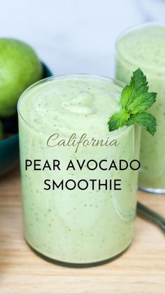 two glasses filled with green smoothie on top of a wooden table