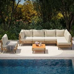 an outdoor living area with couches and tables next to a swimming pool in the backyard