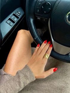 a woman with red nails is sitting in a car