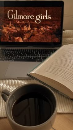 a laptop computer sitting on top of a wooden table next to a cup of coffee