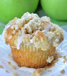 a close up of a muffin on a paper plate with apples in the background