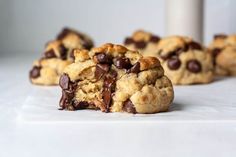 chocolate chip cookies with one broken in half on a white countertop next to another cookie