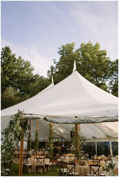 a large white tent with tables and chairs under it