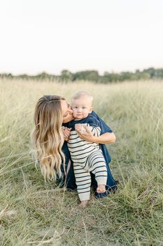 a woman holding a baby in her arms and kissing it's face on the cheek