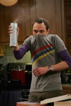 a man standing in a kitchen holding a canister up to his face and looking at the camera