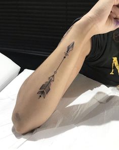 a woman with a tattoo on her arm laying down and pointing to the side,