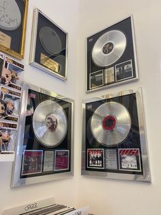 three framed records are on the wall next to each other with pictures and memorabilia around them