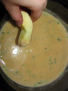 a person is dipping an apple into a bowl