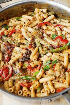 a pan filled with pasta and vegetables on top of a wooden table