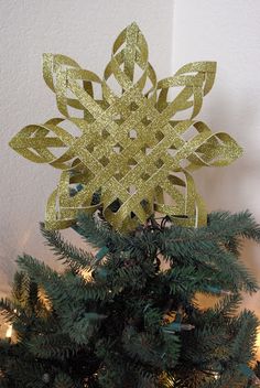 a gold snowflake ornament on top of a christmas tree