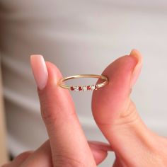 a person holding a gold ring with three small red stones on the inside of it