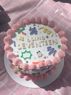 a birthday cake that is sitting on top of a table with pink and white cloth