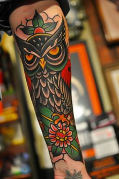 an owl tattoo on the arm and leg with flowers in it's centerpiece