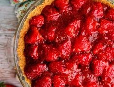 a close up of a pie with strawberries in it on a wooden table top