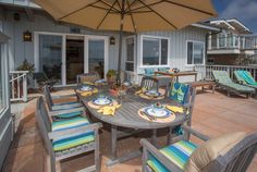 an outdoor dining area with patio furniture and umbrella over the table for sunbathers