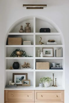 a white book shelf filled with lots of books and vases on top of it