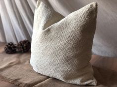 a white pillow sitting on top of a wooden table next to a pinecone