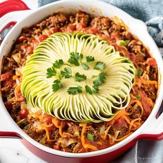 a casserole dish with meat, cheese and avocado garnish