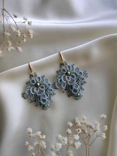 the earrings are made with blue thread and beads