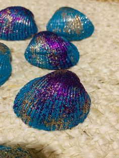 five blue and purple seashells sitting on top of a white carpet next to each other