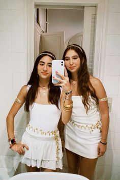 two young women taking a selfie in the bathroom with their cell phone and jewelry