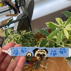 a person holding up a knitted bracelet with a small dog on it's side