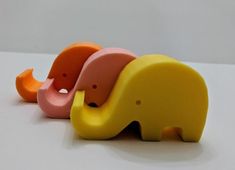 three different colored elephant figurines sitting next to each other on a white surface