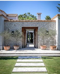 a stone house with steps leading up to the front door and entry way that leads into the back yard