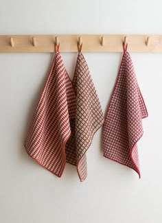 three red and white towels hanging on a coat rack