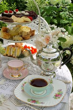 a table topped with plates and cups filled with desserts next to a tea pot