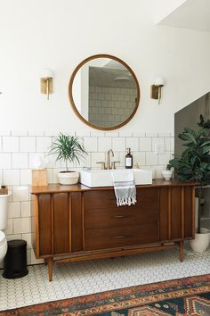 a bathroom vanity with a mirror above it and a rug on the floor next to it